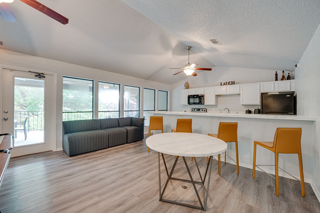 a living room with a round table and a kitchen with a couch at Indian Creek Apartments, Carrollton