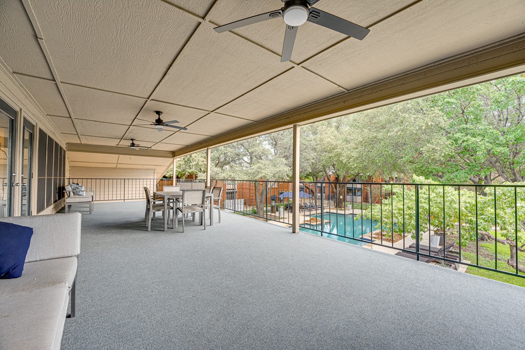 a large covered porch with a pool and a table and chairs at Indian Creek Apartments, Carrollton, 75007