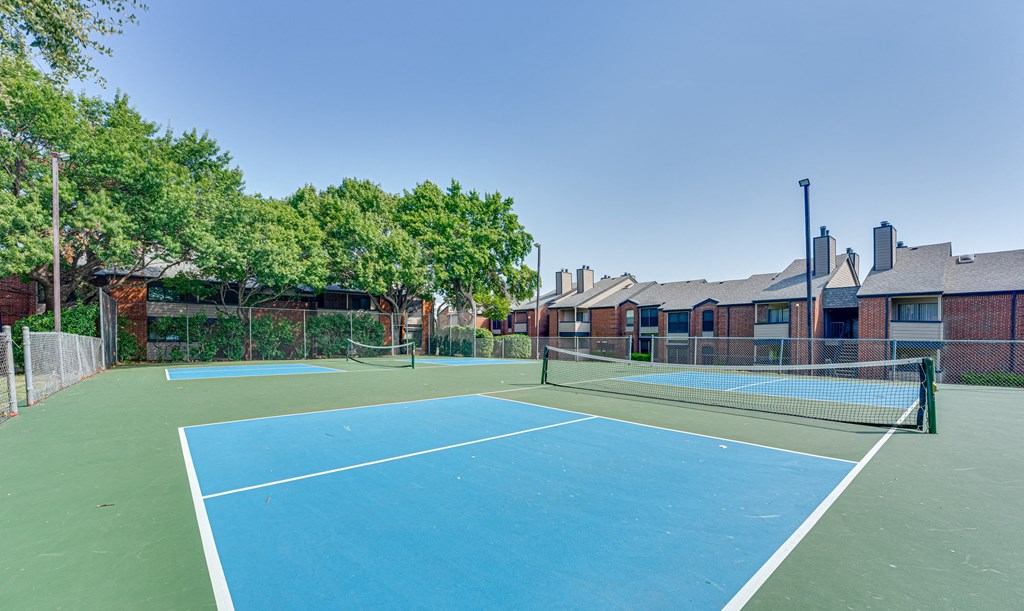 two tennis courts with apartments in the background at Indian Creek Apartments, Carrollton, Texas