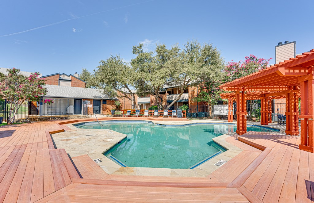 a swimming pool with wooden decking and a poolside cabana and a house at Indian Creek Apartments, Carrollton, 75007