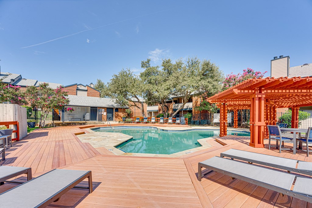 a swimming pool with a wooden deck with tables at Indian Creek Apartments, Carrollton, TX, 75007
