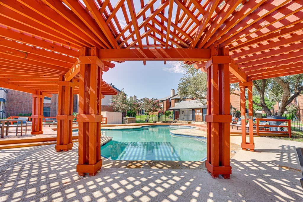 a backyard with a pool and a wooden pergola at Indian Creek Apartments, Texas