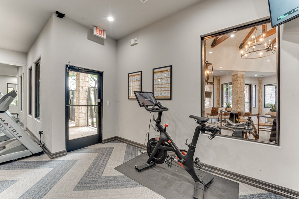 A room with a treadmill, a stationary bike and a mirror at Limestone Ranch Apartments, Lewisville, Texas