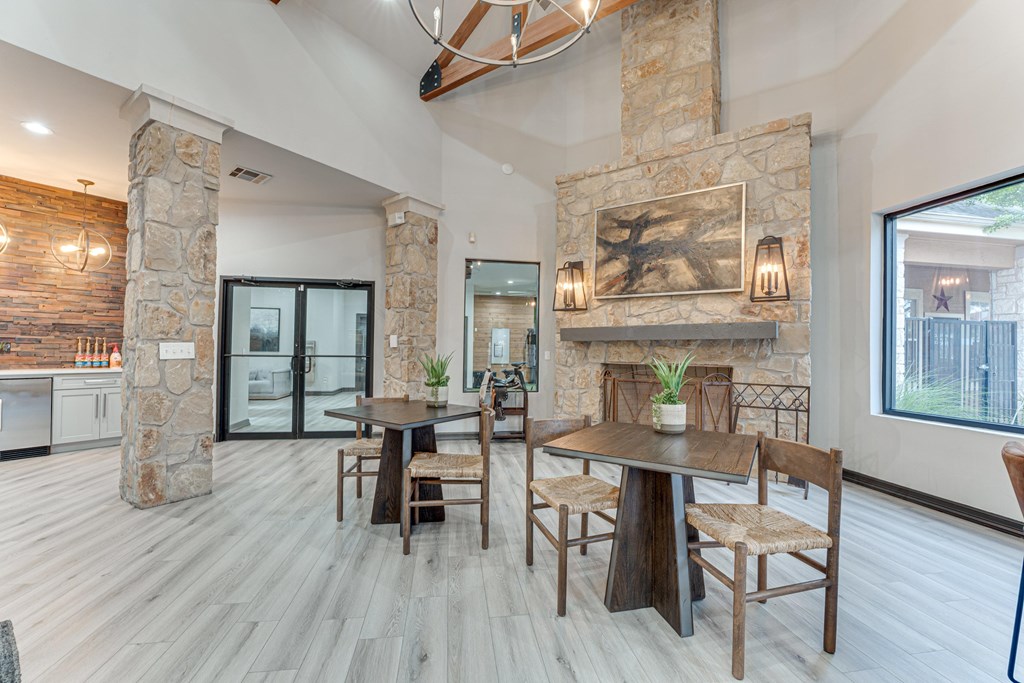 A modern dining room with a stone fireplace and wooden furniture at Limestone Ranch Apartments, Lewisville, TX