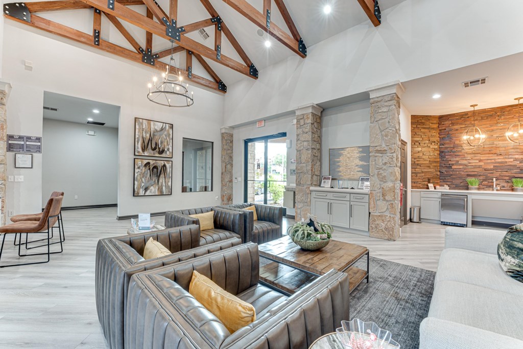 A modern living room with a large grey sofa and a stone fireplace at Limestone Ranch Apartments, Lewisville, TX