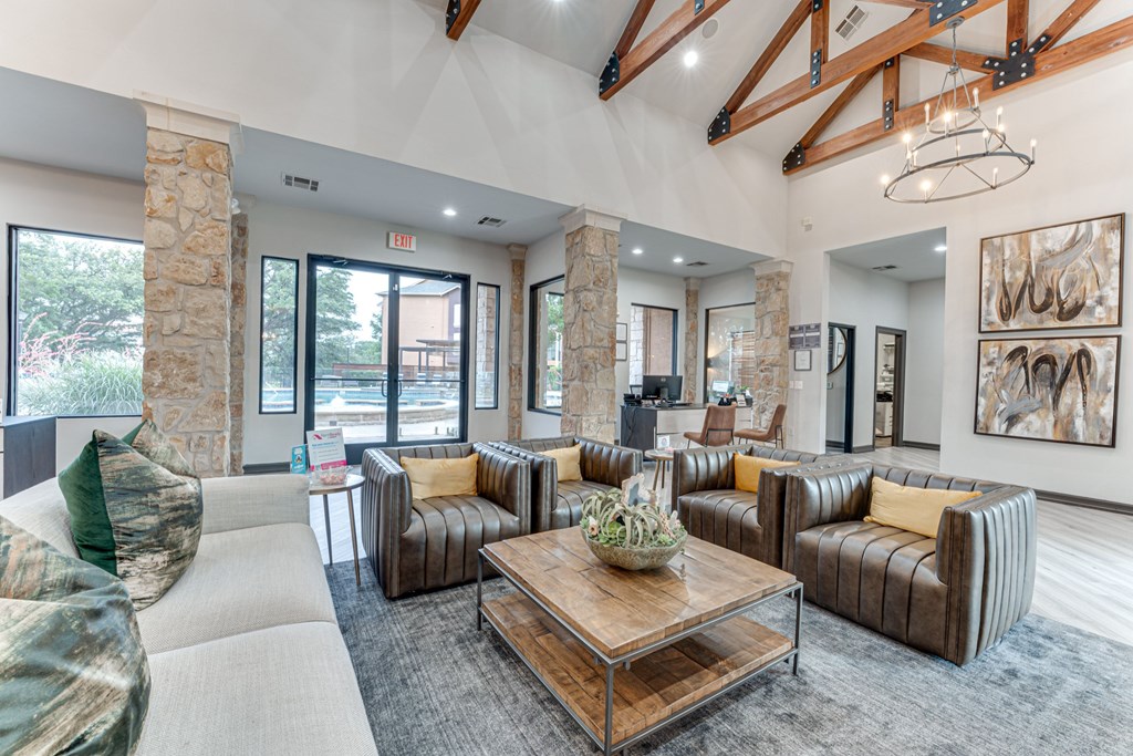 A living room with a large couch, a coffee table, and a chandelier at Limestone Ranch Apartments, Lewisville, Texas