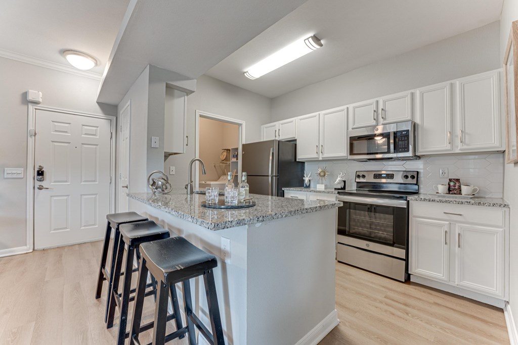 A kitchen with a bar area and stools at Limestone Ranch Apartments, Lewisville, TX, 75067