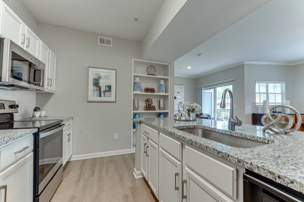 A kitchen with white cabinets and granite countertops at Limestone Ranch Apartments, Texas