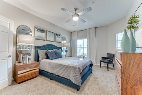 A bedroom with a bed, chair, and a ceiling fan.