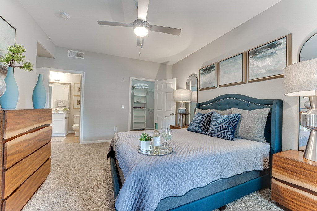 A bedroom with a bed, dresser, and ceiling fan at Limestone Ranch Apartments, Lewisville 75067