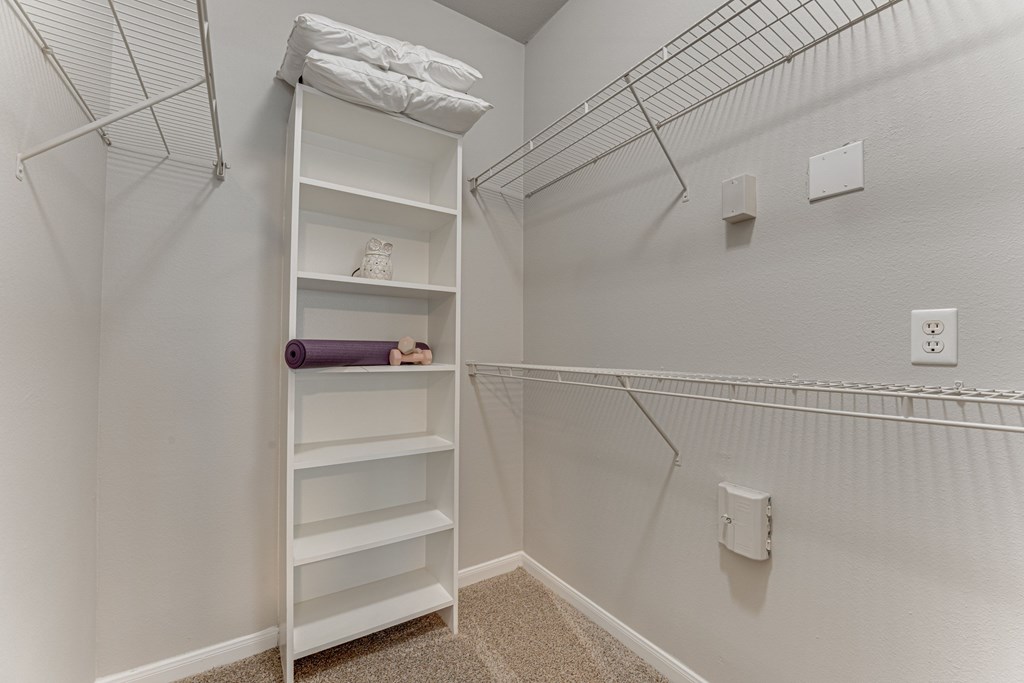 A white shelving unit with a purple yoga mat on the bottom shelf at Limestone Ranch Apartments, Lewisville