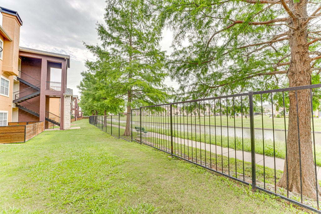 A black metal fence runs along a grassy area at Limestone Ranch Apartments, Lewisville