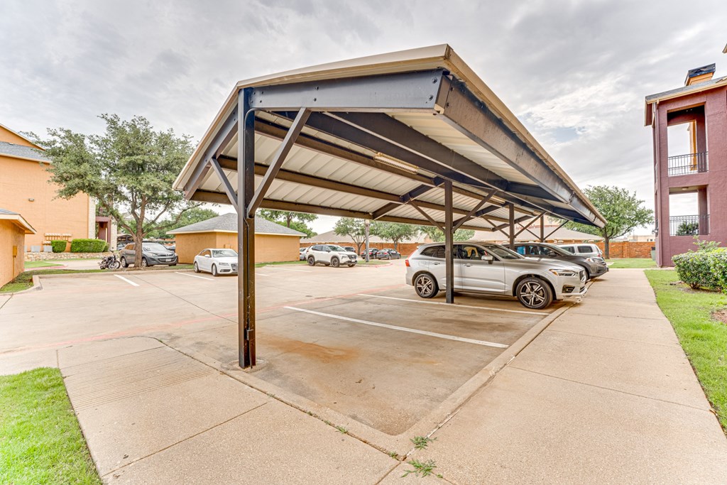 A parking lot with a car parked under a canopy at Limestone Ranch Apartments, Texas