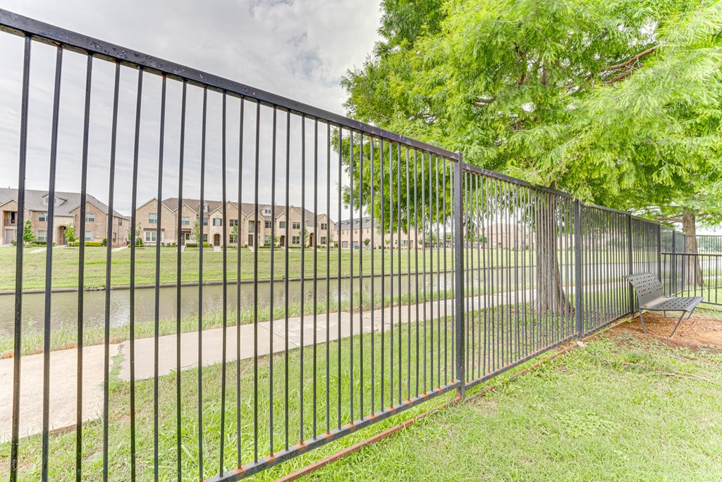 A black metal fence in front of a grassy area and a road at Limestone Ranch Apartments, Texas, 75067