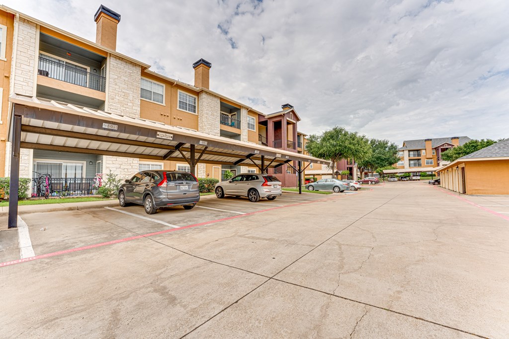 A parking lot with cars and a building in the background at Limestone Ranch Apartments, Lewisville, Texas