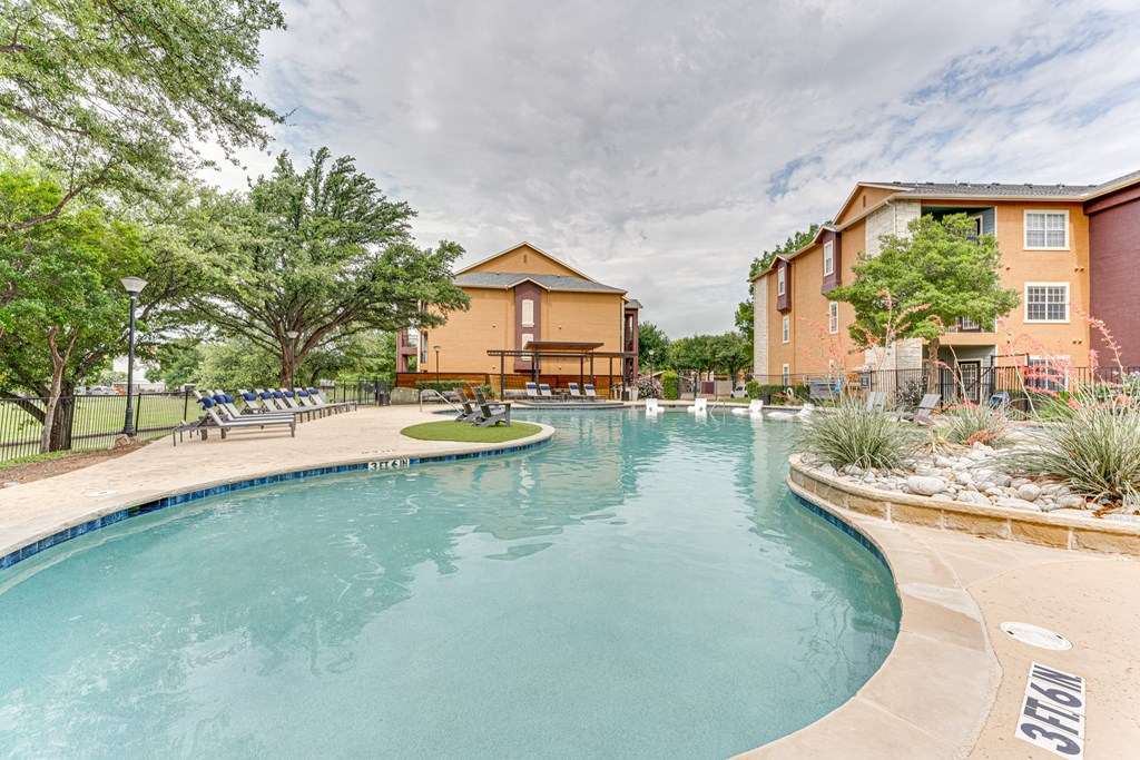 A large swimming pool in front of a building with a yellow roof at Limestone Ranch Apartments, Lewisville, TX, 75067