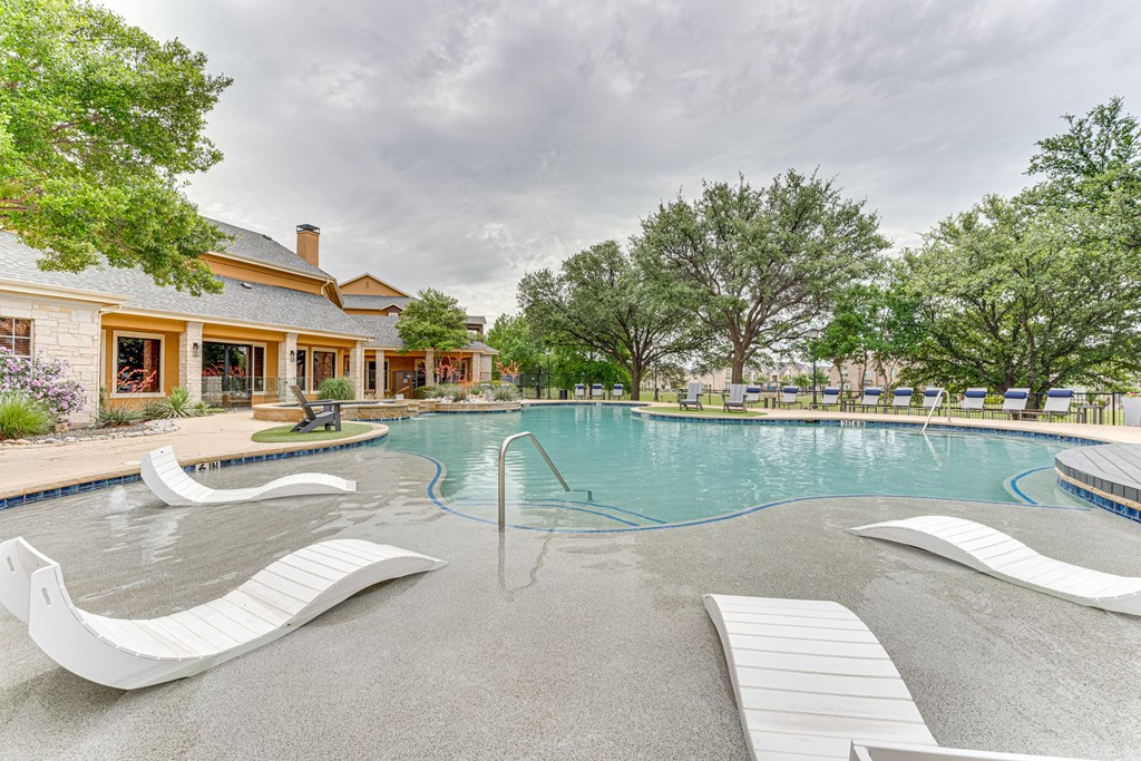 A pool with a white slide and a house in the background at Limestone Ranch Apartments, Lewisville, TX