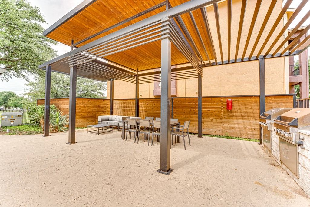 A wooden patio with a table and chairs under a roof at Limestone Ranch Apartments, Lewisville