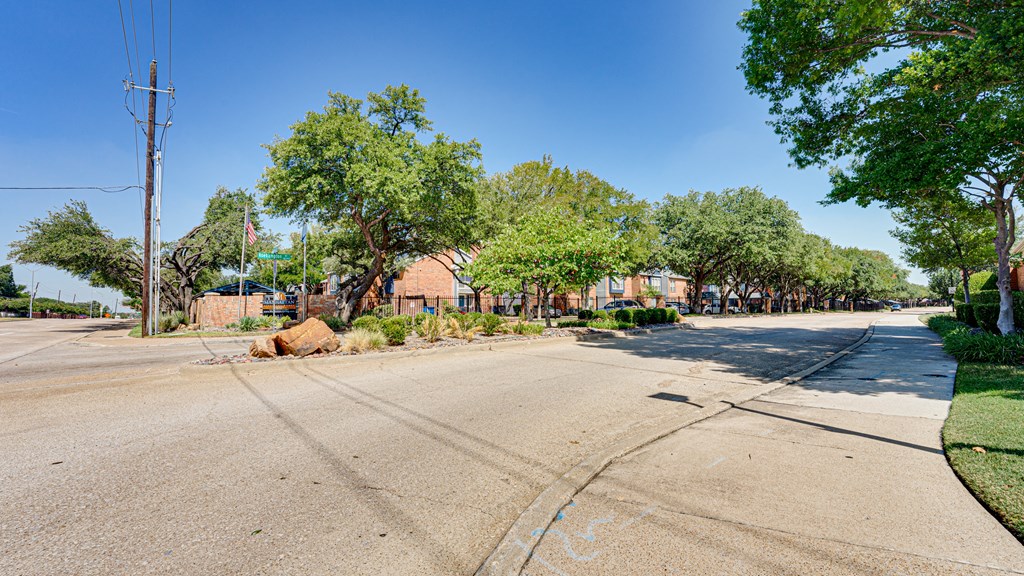 an empty street with houses and trees on the side of the road