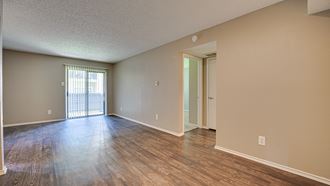 an empty living room with wood floors and a sliding glass door
