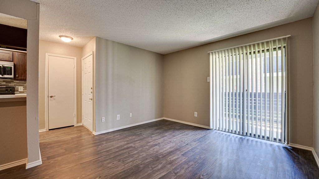 an empty living room with a large window and wood flooring at The Manhattan Apartments, Dallas, TX, 75252