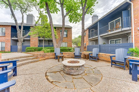 A courtyard with a fire pit surrounded by chairs and trees. at The Manhattan Apartments, Dallas, TX