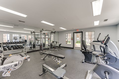 A gym with a variety of equipment including treadmills, weights, and exercise machines. at The Manhattan Apartments, Dallas