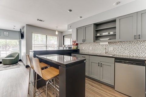 A kitchen with a black countertop and wooden chairs. at The Manhattan Apartments, Dallas, TX