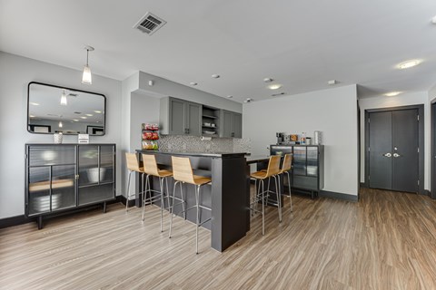 A modern kitchen with a wooden floor and a large island with chairs. at The Manhattan Apartments, Texas