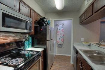 a kitchen with a stove top oven next to a refrigerator at The Manhattan Apartments in Dallas, TX