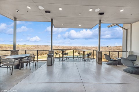 A patio with a table and chairs overlooking a field.
