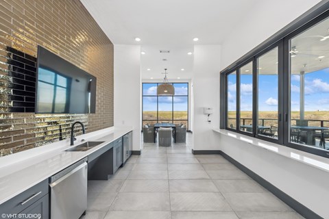A modern kitchen with a brick accent wall and large windows.