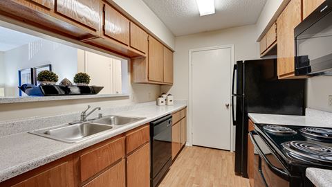 full kitchen with black appliances and wood cabinets at the reserve at walnut creek apartments