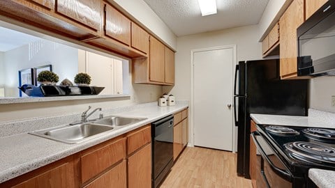 full kitchen with black appliances and wood cabinets at the reserve at walnut creek apartments at Paces Crossing, Denton, TX