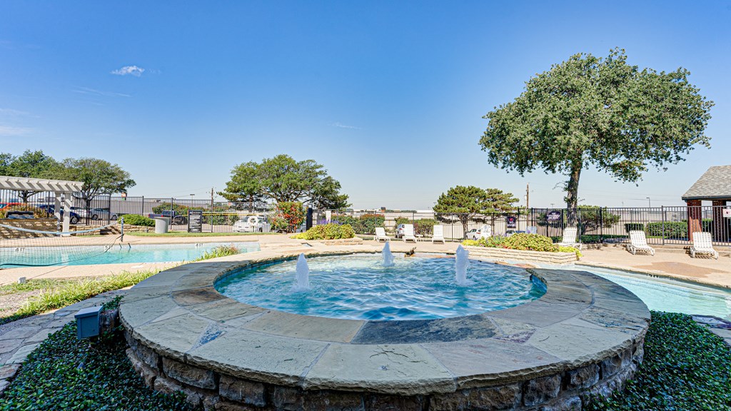 a fountain in a park with a pool and trees at Paces Crossing, Denton