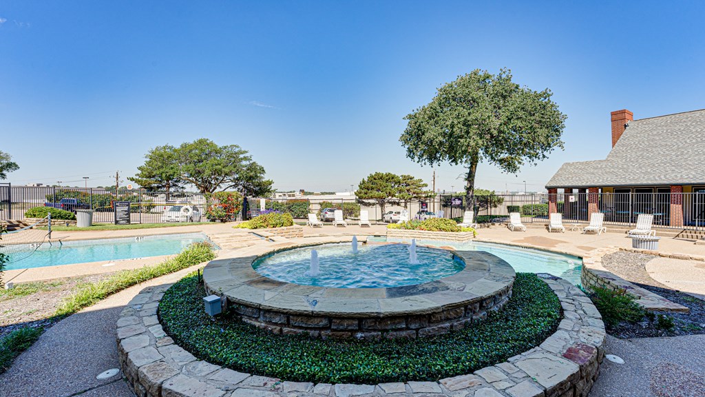 an outdoor pool with a fountain and a building in the background at Paces Crossing, Texas