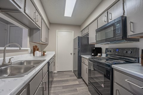A kitchen with a black stove top oven and a black microwave above it.