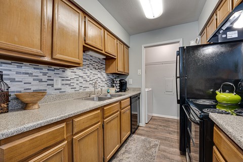 A kitchen with wooden cabinets and a black refrigerator.