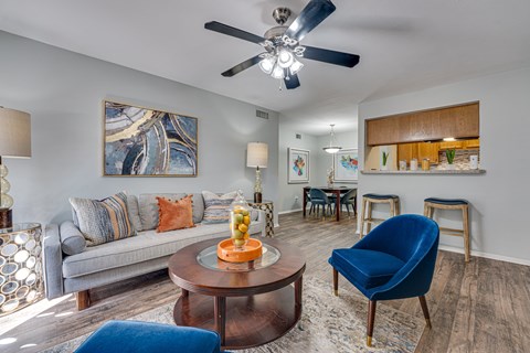 A living room with a grey couch, a blue chair, and a painting on the wall.