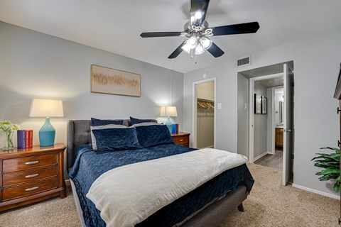 A bedroom with a bed, nightstand, and a ceiling fan.