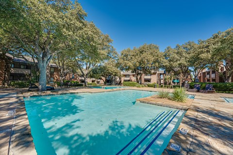 A swimming pool surrounded by trees and houses.