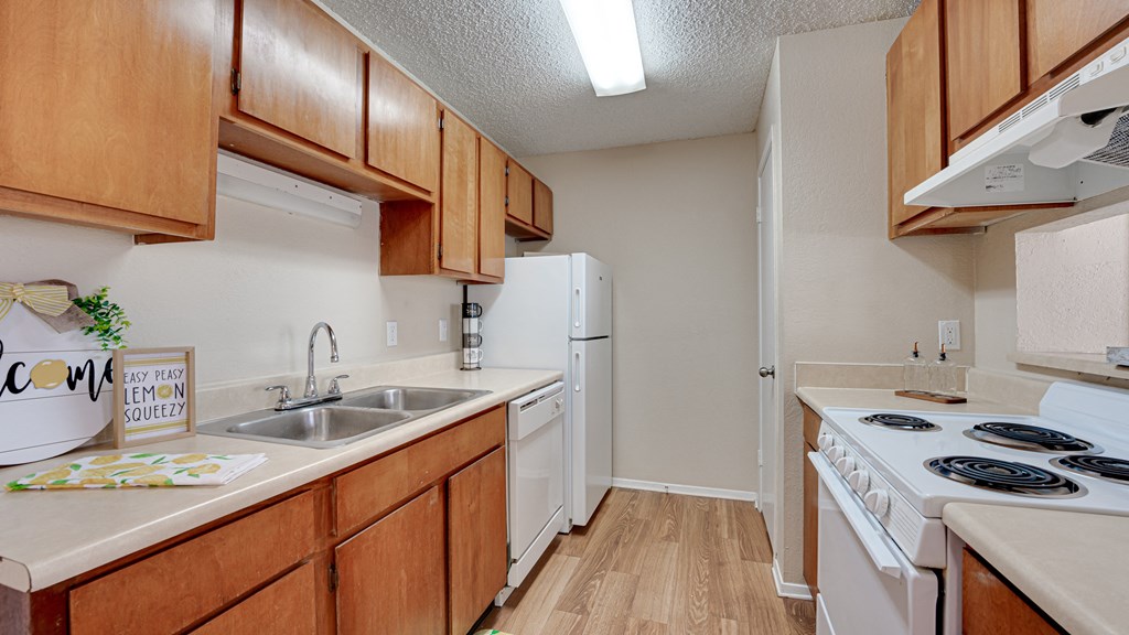 galley kitchen with wood finishes and white appliances  at Arbors Of Cleburne, Cleburne