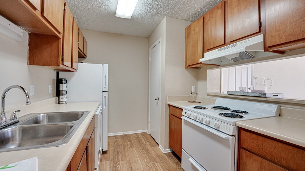 galley kitchen with wood finishes and white appliances  at Arbors Of Cleburne, Texas, 76033