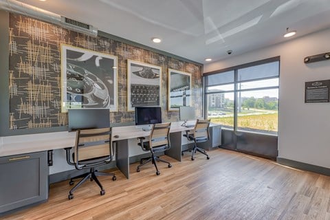 A modern office space with a long table and chairs, a patterned wall, and a view of the outdoors.