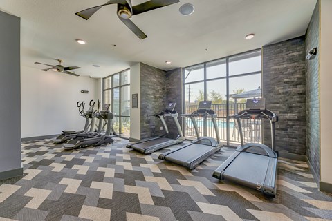 A gym with treadmills and a fan.