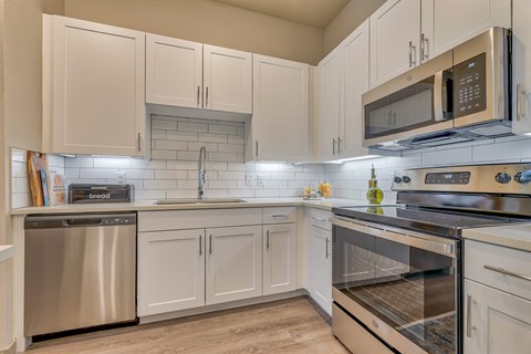 A kitchen with white cabinets and stainless steel appliances.