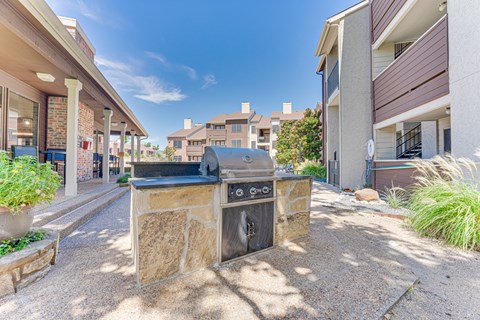 A stone fireplace is in the middle of a gravel courtyard.