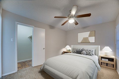 A bedroom with a bed, two lamps, and a ceiling fan.