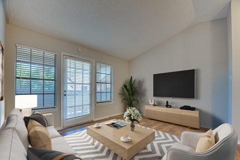 A living room with a grey couch, a wooden coffee table, a flat screen TV and a plant.