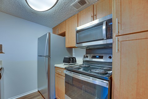 A kitchen with a stove, microwave, and refrigerator.